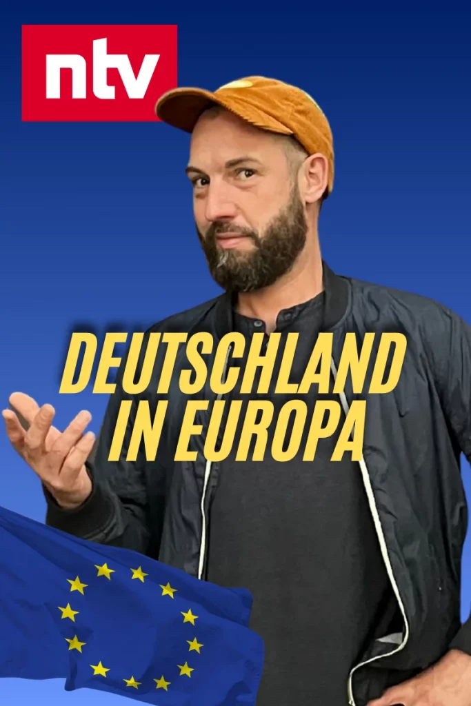 Ein Mann mit dunklem Bart, dunkler Jacke und orangefarbener Kappe steht vor blauem Hintergrund. Oben links ist das rote ntv-Logo zu sehen. In der Mitte des Bildes steht in großen gelben Buchstaben der Text „Deutschland in Europa“. Unten links weht eine EU-Flagge mit gelben Sternen.